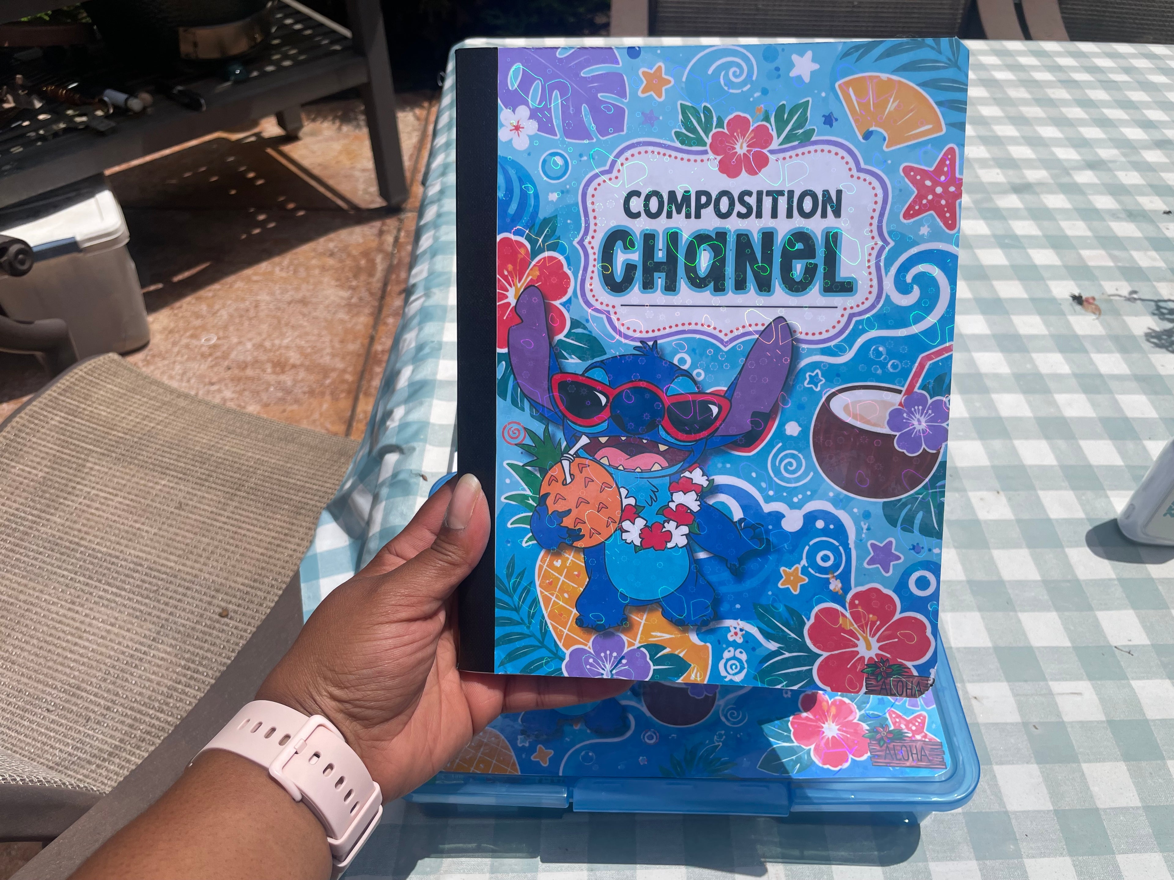 A hand holds a blue notebook or journal featuring a cartoon character on the cover.